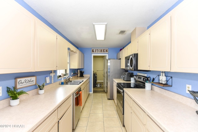 kitchen with stainless steel appliances, light tile patterned flooring, white cabinets, and sink