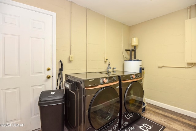 washroom featuring electric panel, washing machine and dryer, water heater, and light hardwood / wood-style flooring