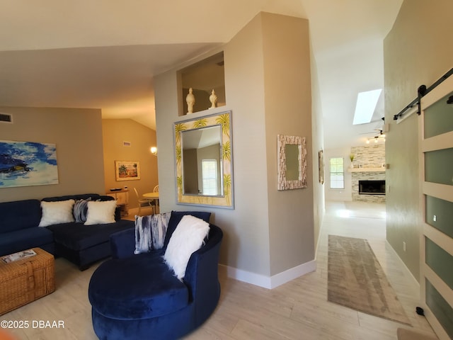 1941 Spruce Creek Lndg, Port Orange, FL 32128 - living room featuring vaulted ceiling, a barn door, light wood-style flooring, and a fireplace