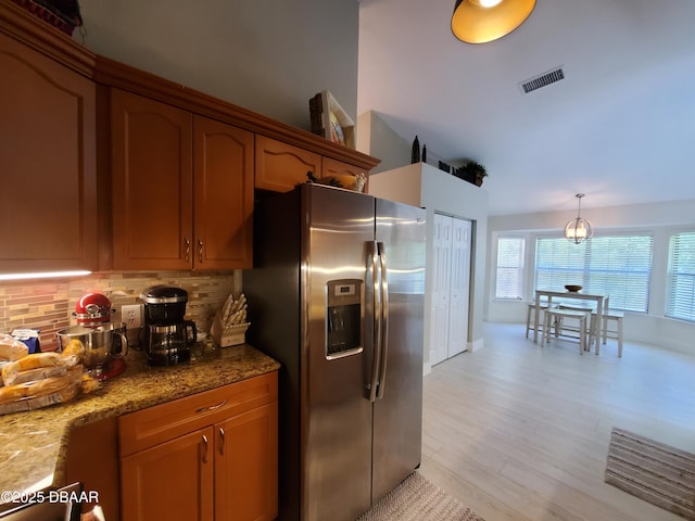 1941 Spruce Creek Lndg, Port Orange, FL 32128 - kitchen with stainless steel refrigerator with ice dispenser, tasteful backsplash, light stone countertops, light wood-style floors, and brown cabinetry