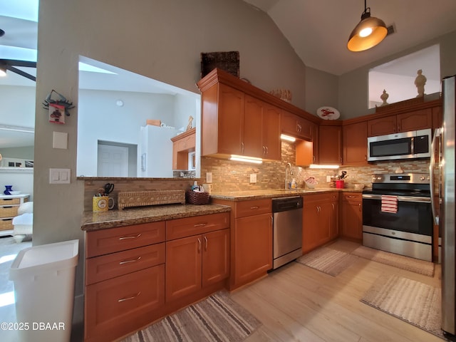 1941 Spruce Creek Lndg, Port Orange, FL 32128 - kitchen featuring stainless steel appliances, light wood finished floors, tasteful backsplash, vaulted ceiling, and light stone countertops