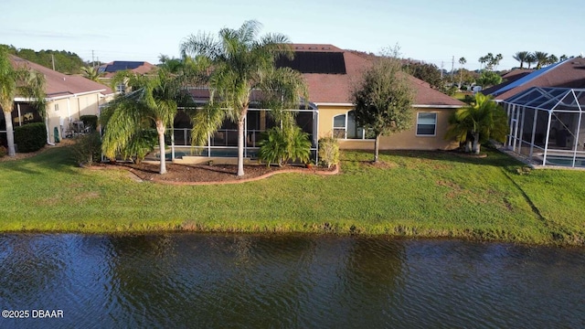 rear view of house featuring a lanai, a water view, and a yard