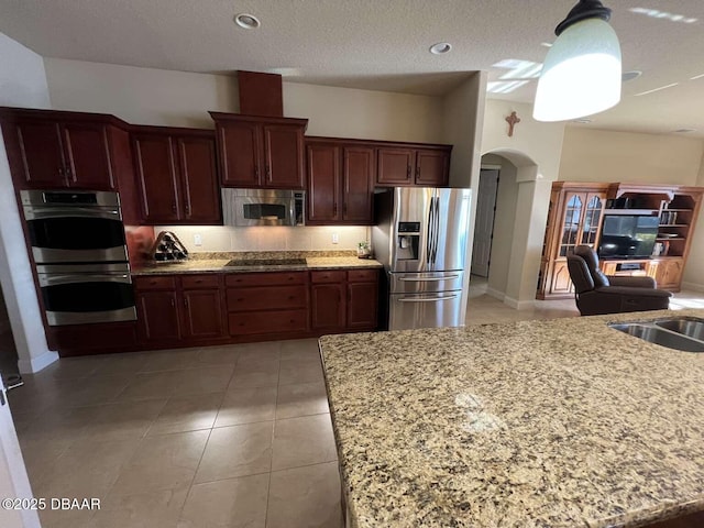 kitchen featuring light stone counters, a textured ceiling, light tile patterned floors, and stainless steel appliances