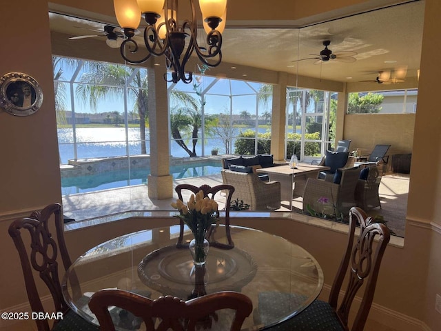 dining room featuring ceiling fan with notable chandelier and a water view