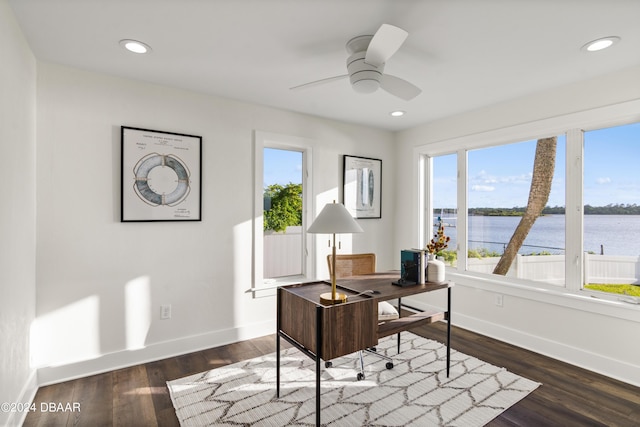 office area with ceiling fan, dark hardwood / wood-style floors, and a water view