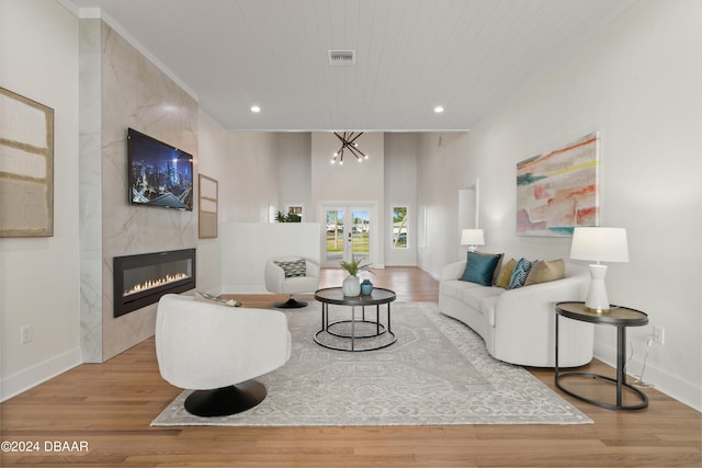 living room with french doors, an inviting chandelier, light hardwood / wood-style floors, a fireplace, and wood ceiling