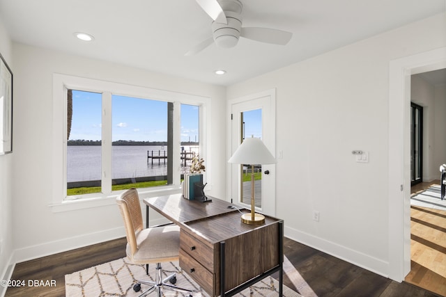 office space featuring dark hardwood / wood-style flooring, ceiling fan, a water view, and a wealth of natural light