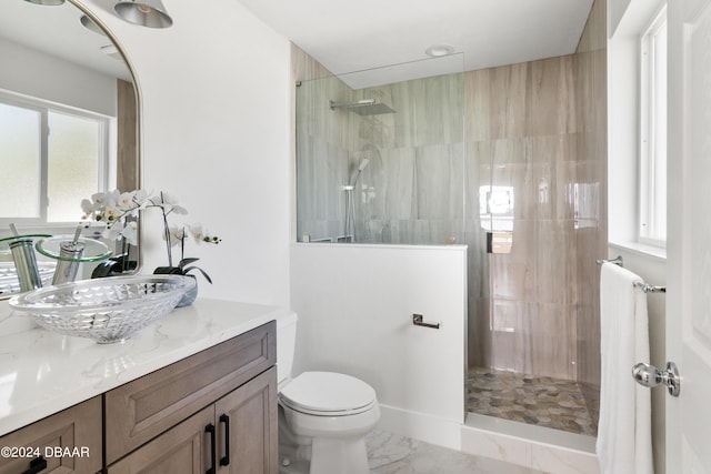 bathroom with a tile shower, vanity, and toilet