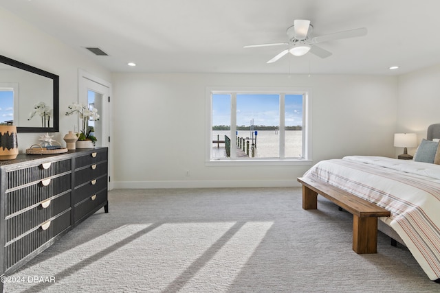 bedroom featuring light colored carpet, ceiling fan, and a water view