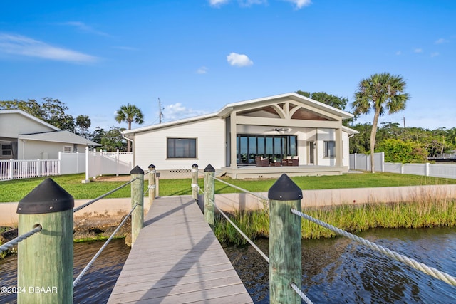 view of dock with a water view and a lawn