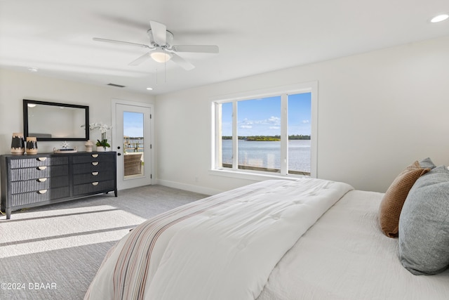 carpeted bedroom featuring access to outside, a water view, and ceiling fan