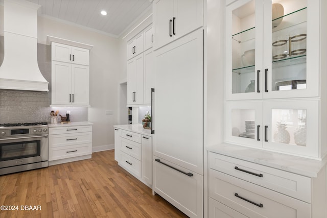 kitchen with white cabinetry, tasteful backsplash, crown molding, range with two ovens, and custom range hood