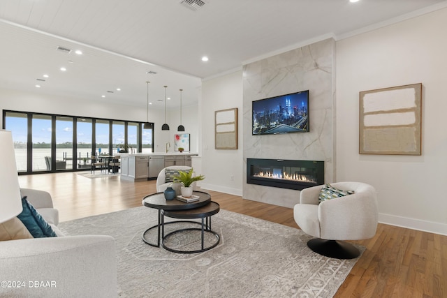 living room featuring sink, wooden ceiling, light wood-type flooring, a fireplace, and ornamental molding