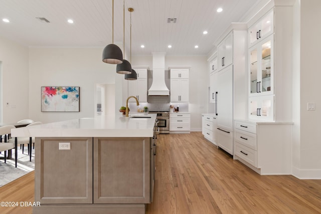 kitchen with custom range hood, premium appliances, sink, a large island with sink, and white cabinetry