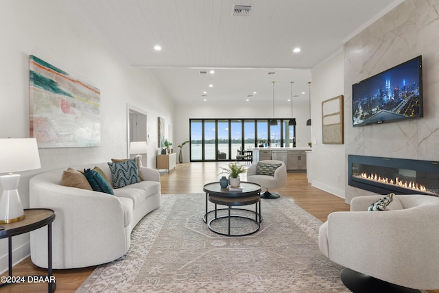 living room with a fireplace, light wood-type flooring, and wood ceiling