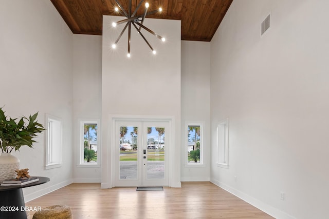 unfurnished living room with french doors, high vaulted ceiling, wood ceiling, and an inviting chandelier