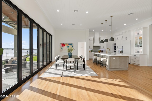 kitchen with decorative light fixtures, light hardwood / wood-style floors, a spacious island, and white cabinetry