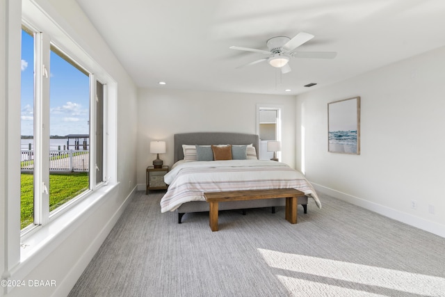 bedroom with multiple windows, ceiling fan, and light carpet