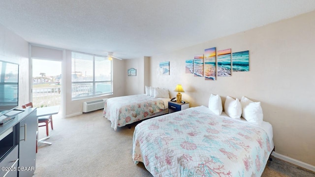 bedroom featuring a textured ceiling, a wall mounted AC, baseboards, and carpet floors