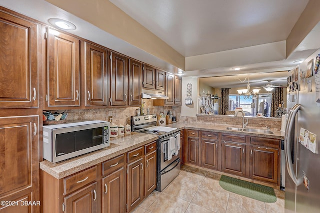 kitchen featuring backsplash, appliances with stainless steel finishes, light tile patterned floors, sink, and a chandelier