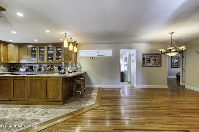 kitchen featuring a kitchen breakfast bar, dark hardwood / wood-style flooring, backsplash, pendant lighting, and a chandelier