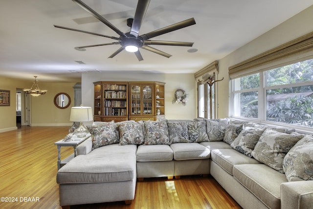 living room with light hardwood / wood-style floors and ceiling fan with notable chandelier