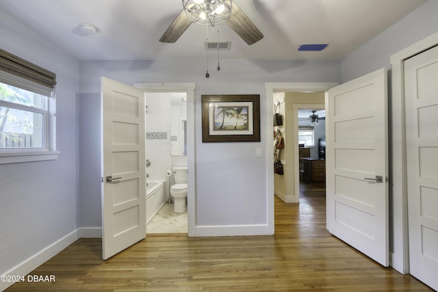 unfurnished bedroom with light wood-type flooring, ensuite bath, and ceiling fan