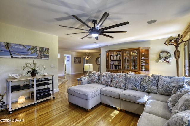 living room with ceiling fan with notable chandelier and hardwood / wood-style flooring