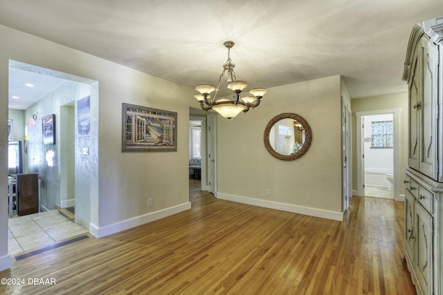 unfurnished dining area with light wood-type flooring and an inviting chandelier