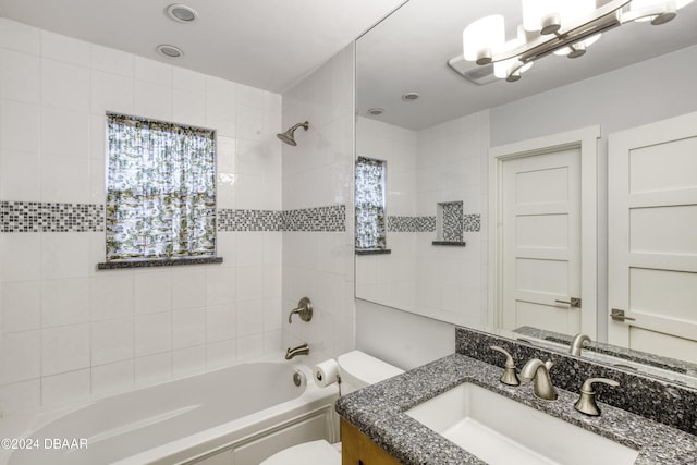 full bathroom with vanity, a healthy amount of sunlight, tiled shower / bath combo, and toilet