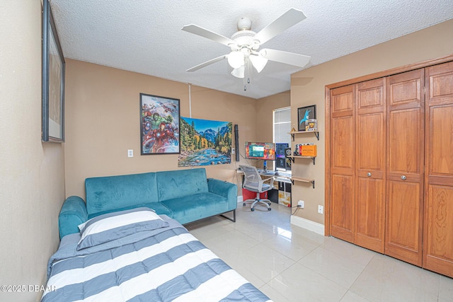 tiled bedroom featuring a closet, ceiling fan, and a textured ceiling