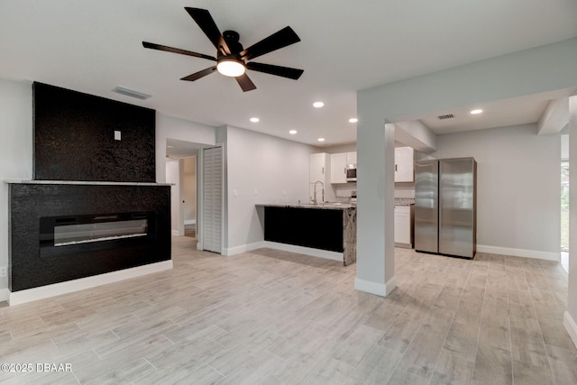 unfurnished living room featuring ceiling fan and light wood-type flooring