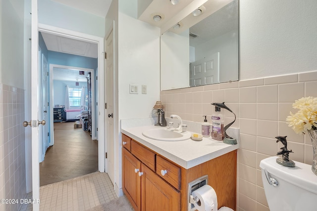 bathroom featuring toilet, vanity, tile walls, and tile patterned floors