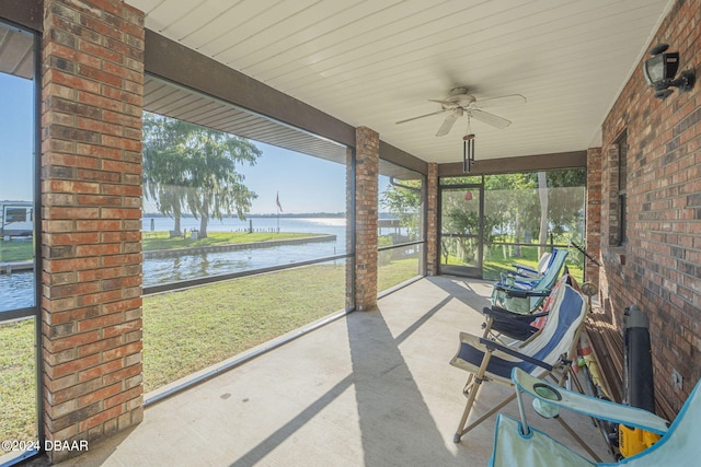 unfurnished sunroom with a water view, a healthy amount of sunlight, and ceiling fan