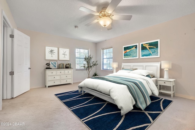 bedroom with a textured ceiling, light colored carpet, and ceiling fan