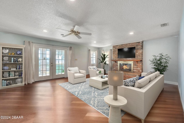 living room featuring a fireplace, a textured ceiling, hardwood / wood-style flooring, and french doors