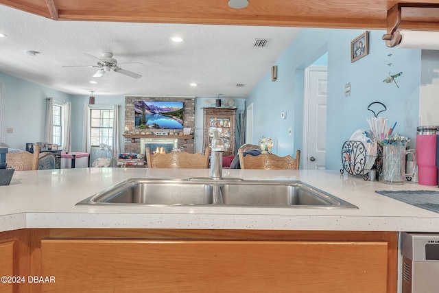 kitchen with ceiling fan, a textured ceiling, sink, and dishwasher