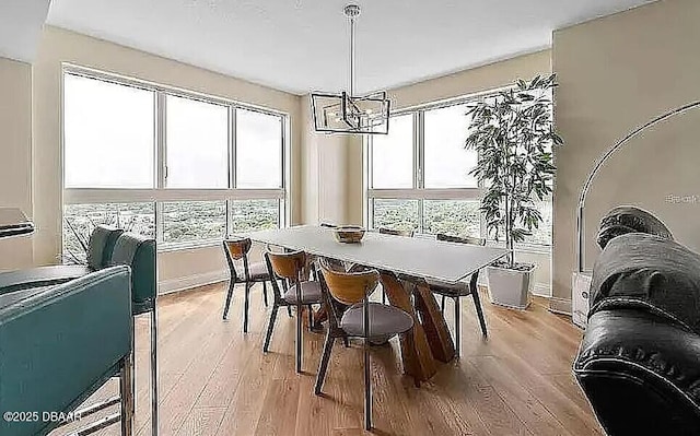 dining area with an inviting chandelier, light wood-style floors, and baseboards