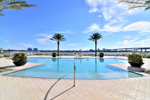 pool with a patio, fence, and a water view