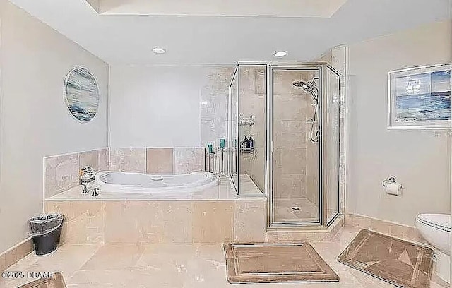 bathroom featuring toilet, a shower stall, and a garden tub