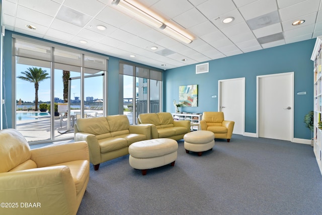 living area featuring visible vents, baseboards, carpet, floor to ceiling windows, and a paneled ceiling