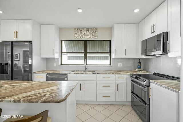 kitchen with tasteful backsplash, stainless steel appliances, sink, light tile patterned floors, and white cabinetry