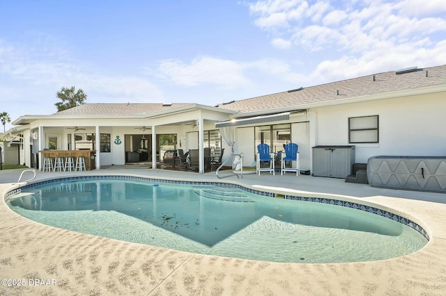 view of swimming pool featuring ceiling fan, an outdoor bar, and a patio