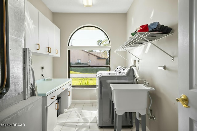 clothes washing area with cabinets, light tile patterned floors, separate washer and dryer, and plenty of natural light