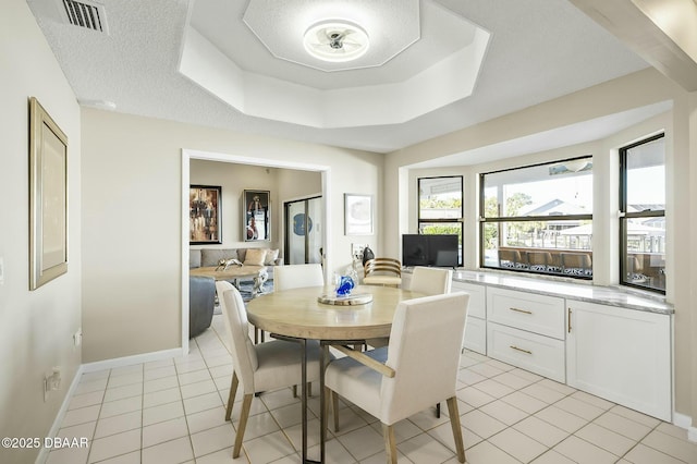 tiled dining room with a tray ceiling