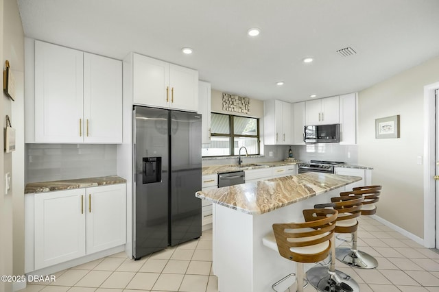 kitchen featuring appliances with stainless steel finishes, backsplash, sink, white cabinets, and a kitchen island