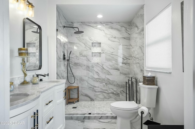 bathroom with a tile shower, vanity, and toilet