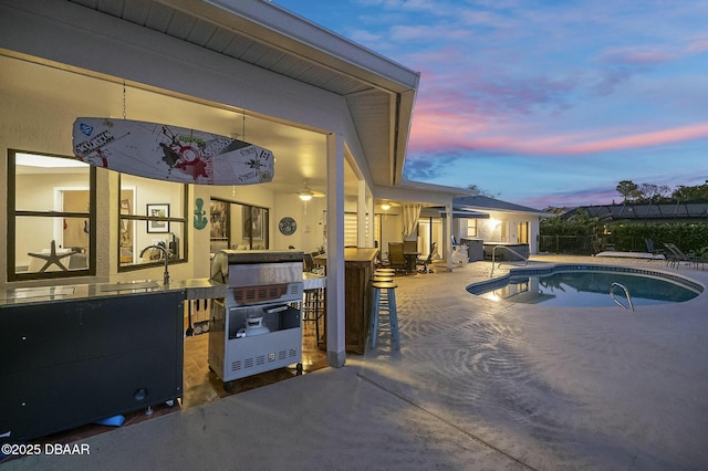 pool at dusk with a patio area and exterior bar