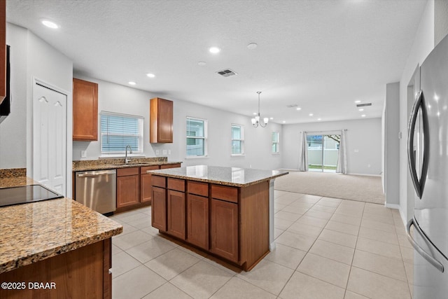 kitchen featuring a kitchen island, appliances with stainless steel finishes, sink, and light stone counters