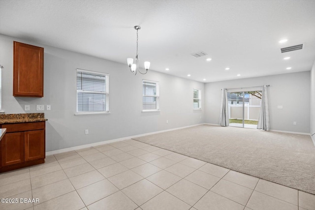 unfurnished dining area with light colored carpet and a chandelier